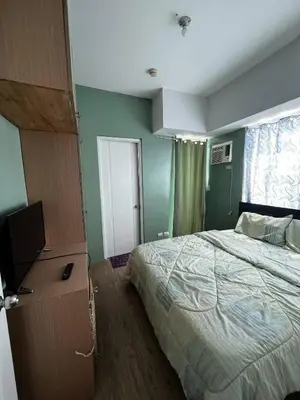 a bedroom with a bed and a dresser with a television at Anuva Condo Staycation in Manila