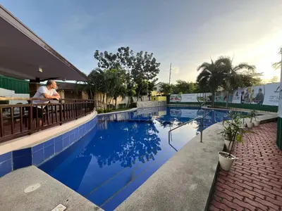 a man sitting at a bar next to a swimming pool at Anuva Condo Staycation in Manila