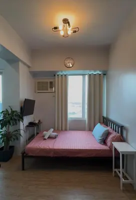 a bedroom with a large bed with a window at Anuva Condo Staycation in Manila
