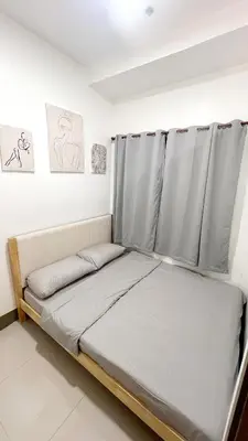 a bed in a room with grey curtains at Condo with Mall in Manila