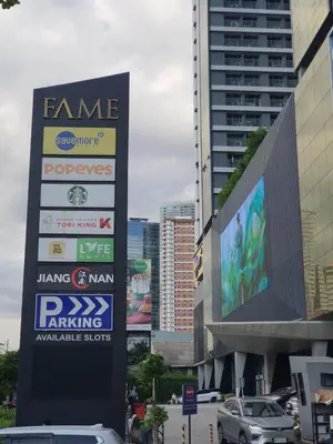 a sign in front of a parking lot with cars at Condo with Mall in Manila