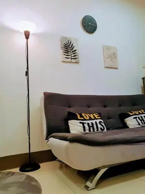 a living room with a couch and a clock on the wall at Condo with Mall in Manila