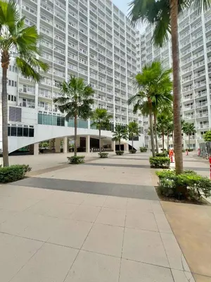 a large building with palm trees in front of it at Shore 607 A bayview moa in Manila