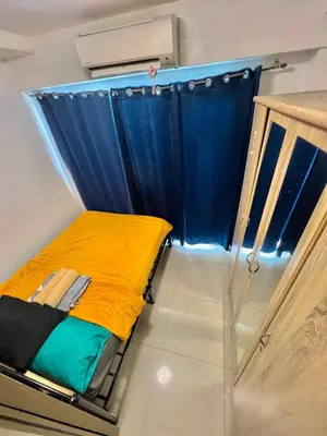 a small bed in a room with a blue curtain at Shore 607 A bayview moa in Manila