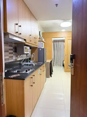 a kitchen with wooden cabinets and a black counter top at Zeth's Place at Shell Residences Near MOA and NAIA in Manila