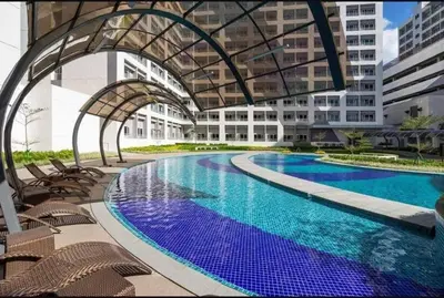 a large swimming pool with chairs and a building at 2243 Taguig Condo Near Airport and BGC in Manila
