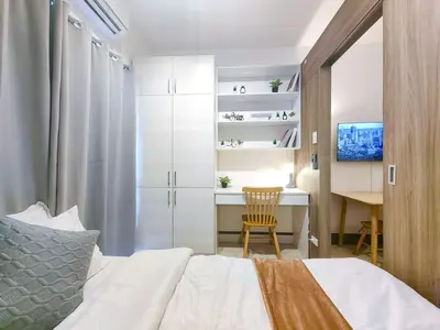 a bedroom with a bed and a desk and a table at 1BR Condotel with Balcony at FAME Residences #FM16-1 in Manila