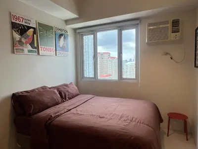 a bedroom with a bed in a room with two windows at Cozy Nook l Accessible LRT QC l Wifi & Netflix in Manila
