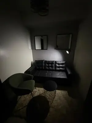 a dark living room with a couch and a chair at NFr in Manila