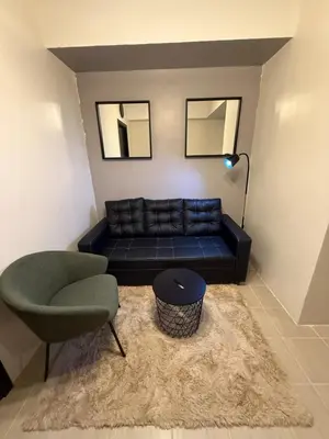 a living room with a black couch and a chair at NFr in Manila