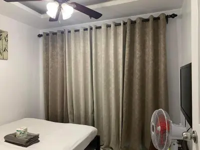 a room with a bed and a fan and a curtain at Birch Tower a9 front of Robinson PlaceRizal park in Manila