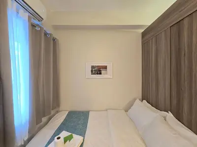 a small bedroom with a bed and a window at 1BR Condotel with Balcony at FAME Residences #FM62-1 in Manila