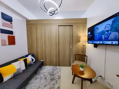 a living room with a couch and a flat screen tv at 1BR Condotel with Balcony at FAME Residences #FM01-1 in Manila