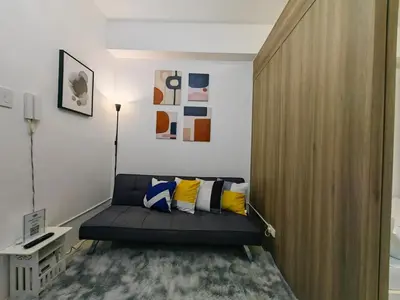 a living room with a couch and a wooden door at 1BR Condotel with Balcony at FAME Residences #FM01-1 in Manila