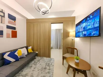 a living room with a couch and a table and a tv at 1BR Condotel with Balcony at FAME Residences #FM01-1 in Manila