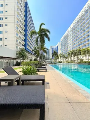 a swimming pool with benches and a large building at Sea Residences Manila Condotel by Paul in Manila