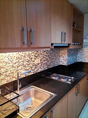 a kitchen with a sink and wooden cabinets at Shell Residences MOA - JOSH in Manila