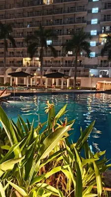 a large swimming pool with a building in the background at Shell Residences MOA - JOSH in Manila