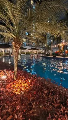 a pool with a palm tree and lights in a building at Shell Residences MOA - JOSH in Manila