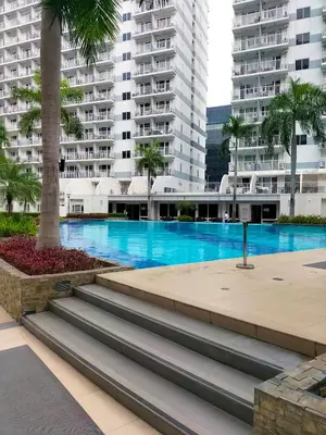 a swimming pool in a city with tall buildings at Shell Residences MOA - JOSH in Manila