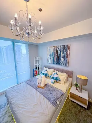 a bedroom with a large bed and a chandelier at Azure Staycation in Manila