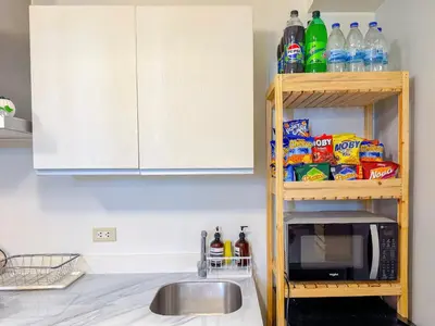 a kitchen with a microwave and a shelf with food at Azure Staycation in Manila