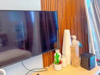 a tv sitting on a desk with a table with at Azure Staycation in Manila