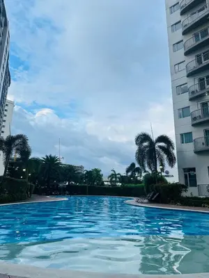 a large swimming pool between two tall buildings at Affordable Condo Near SM Southmall in Manila