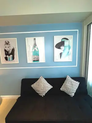a living room with a black couch and pictures on the wall at Positano 909 in Manila
