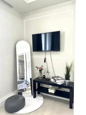 a living room with a table with a tv on the wall at Positano 909 in Manila