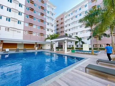 a man walking by a swimming pool in front of a building at Eco Suite Hope Residences Trece in Trece Martires