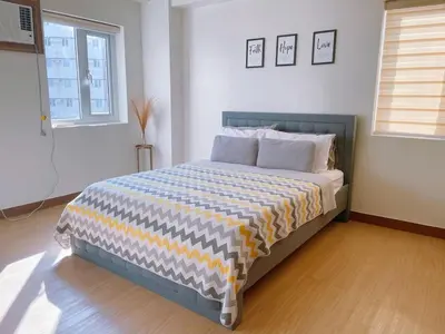 a bedroom with a bed with a striped comforter at Eco Suite Hope Residences Trece in Trece Martires