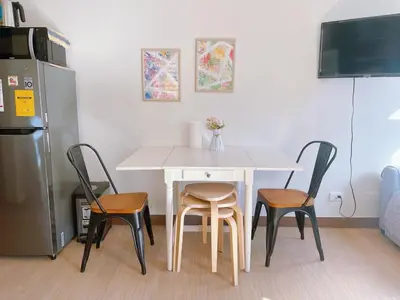 a table with four chairs and a white table and a refrigerator at Eco Suite Hope Residences Trece in Trece Martires