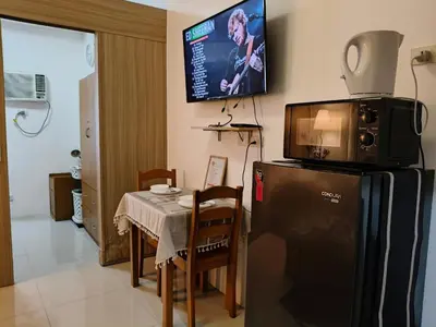 a kitchen with a table and a tv on top of a refrigerator at Shore Residences - Cozy 1BR Apartment near MOA in Manila