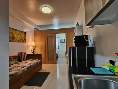a kitchen with a sink and a refrigerator in a room at Shore Residences - Cozy 1BR Apartment near MOA in Manila