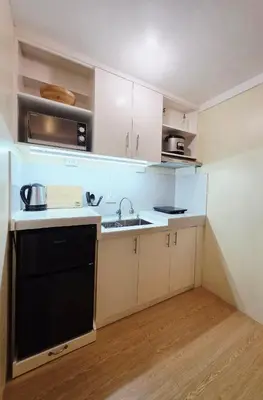 a kitchen with white cabinets and a black dishwasher at Urban Oasis for 7 with 200 mbps & Netflix in Manila