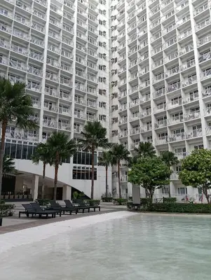 a large apartment building with benches and palm trees at Shore moa view in Manila