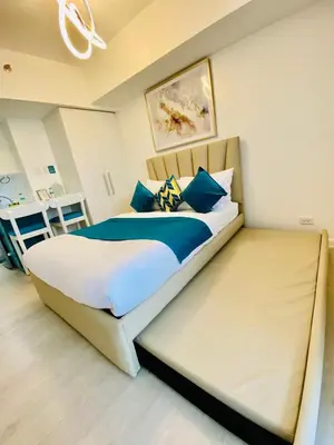 a bedroom with a large bed with blue pillows at SM Bicutan Condo by Santorini in Manila