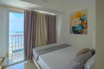 a bedroom with a bed and a window with a balcony at Paradise Staycation at South in Manila