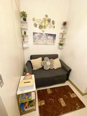 a small living room with a couch and a clock at Paradise Staycation at South in Manila