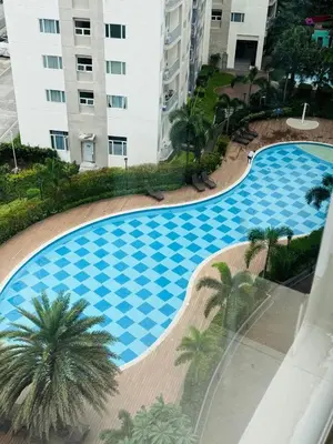a large swimming pool with palm trees in front of a building at Paradise Staycation at South in Manila