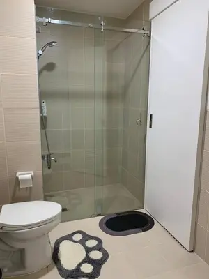 a bathroom with a toilet and a glass shower at Bright & Cozy High-Rise Condo in Pulong Cacawate