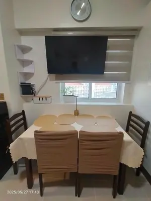 a dining room table with chairs and a flat screen tv at 1123 Field Res Condo by Bambie free drinking water in Manila
