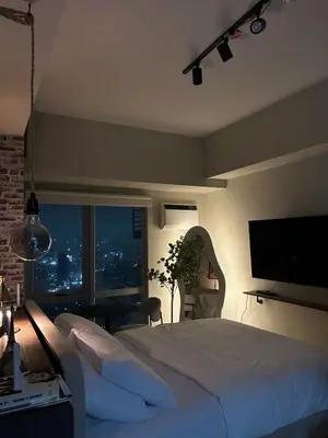 a bedroom with a large bed with a flat screen tv at Trescape Studio in Manila