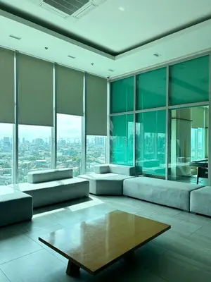 a living room with couches and a table and windows at Trescape Studio in Manila