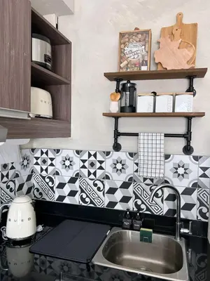 a kitchen with a sink and black and white tiles at Trescape Studio in Manila