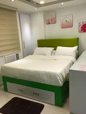 a bedroom with a large bed with a green headboard at One Palm Tree Condo in Manila