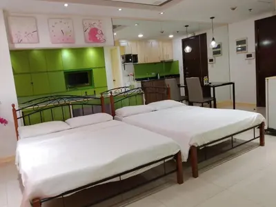 two beds in a room with a kitchen at One Palm Tree Condo in Manila