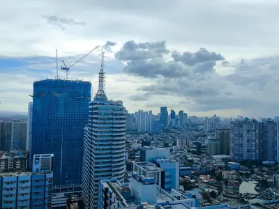 a city with a crane on top of a building at 1BR Condotel with Balcony at FAME Residences #FM03-1 in Manila