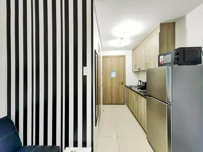 a kitchen with a refrigerator and a black and white striped wall at 1BR Condotel with Balcony at FAME Residences #FM06-1 in Manila